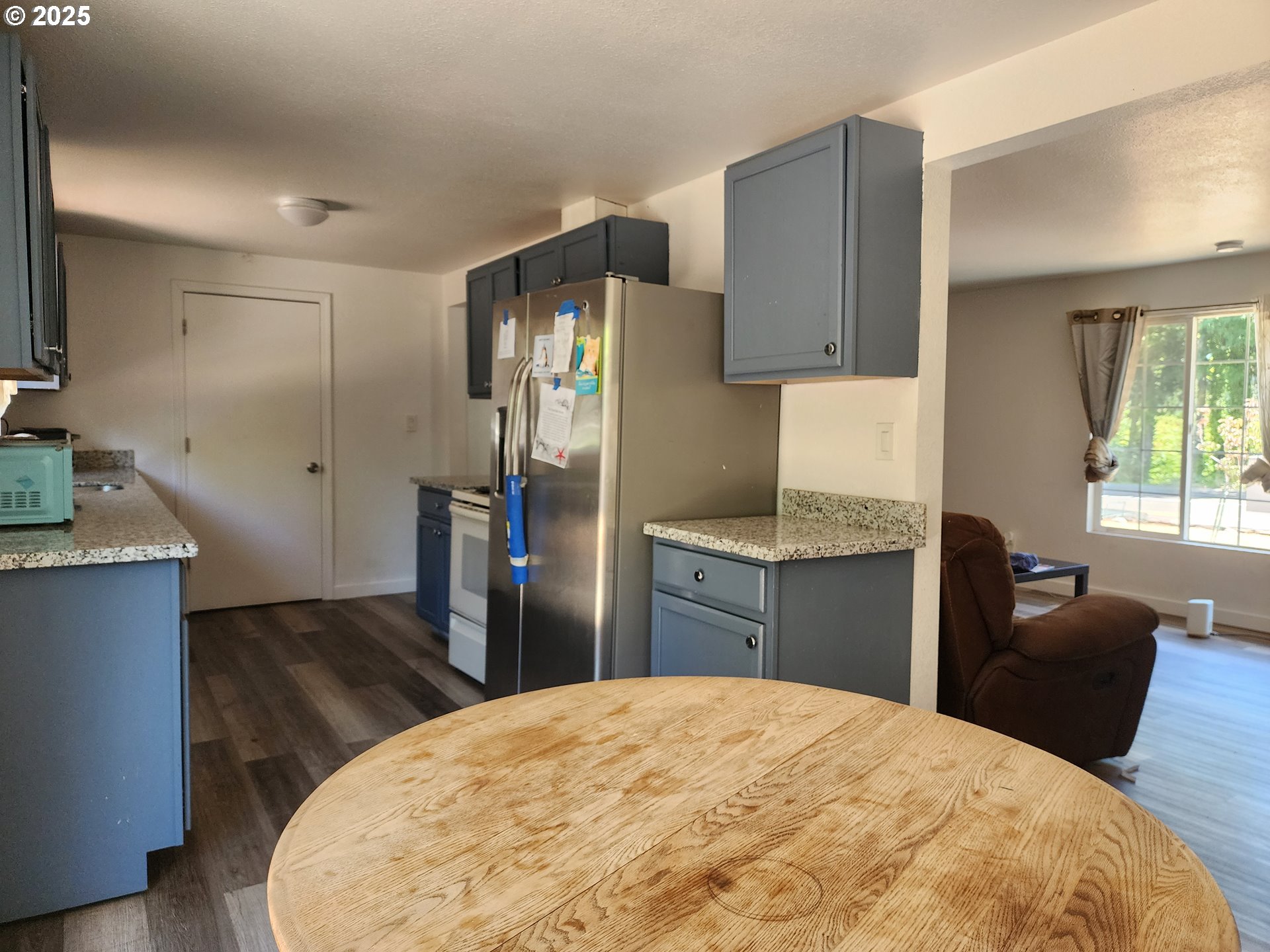 4061 Hawthorne Avenue Northeast Salem, OR 97301 - Photo 5 of 13 a kitchen with stainless steel appliances kitchen island granite countertop a refrigerator a stove and a sink with wooden floor