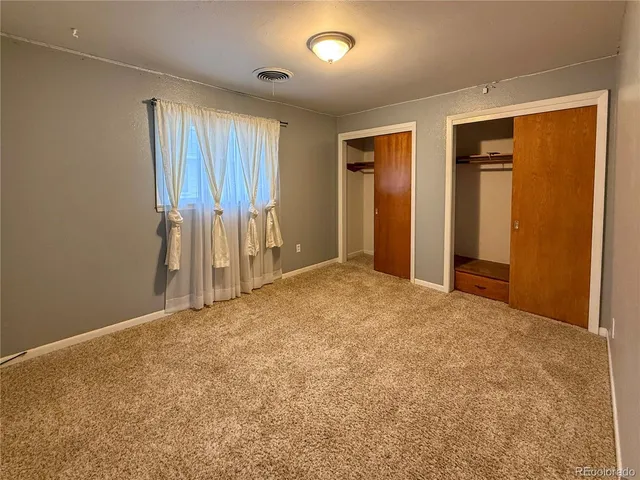 an empty room with windows and cabinet