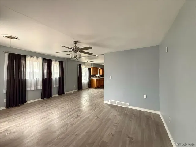 a view of a big room with wooden floor and windows