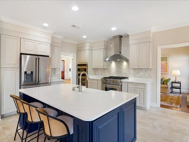 a kitchen with stainless steel appliances a dining table chairs stove refrigerator and cabinets