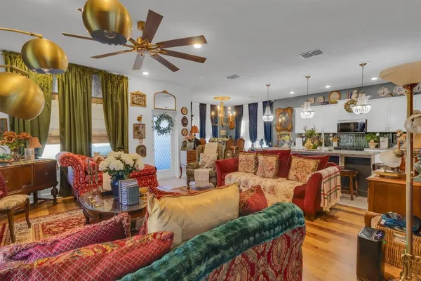 a living room with furniture kitchen view and a chandelier