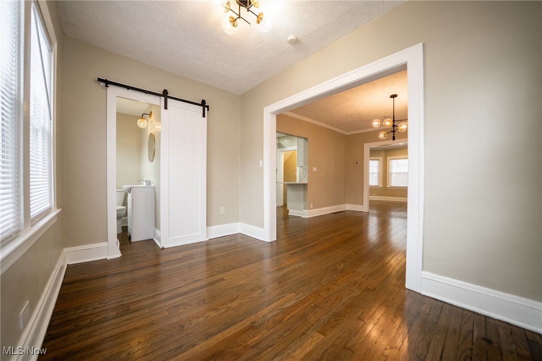 3816 Summit Park Road Cleveland Heights, OH 44121 - Photo 8 of 35 Spare room featuring a barn door, dark wood-type flooring, a chandelier, and a textured ceiling