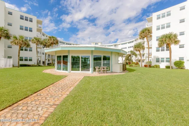 a living room with couches a dining table and chandelier with a large window