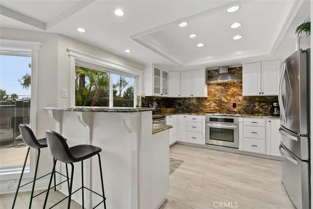 a kitchen with granite countertop white cabinets and stainless steel appliances