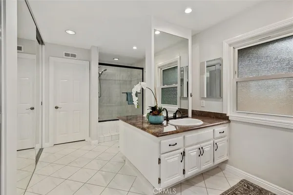a en suite bathroom with a granite countertop sink and a mirror