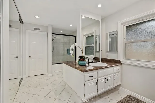 a en suite bathroom with a granite countertop sink and a mirror