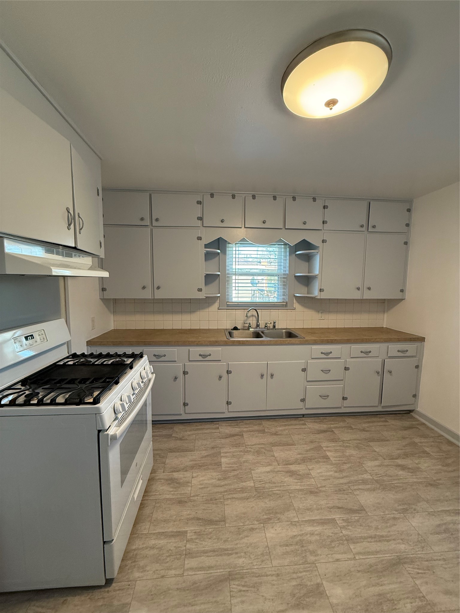 706 Alice Street Sweeny, TX 77480 - Photo 4 of 8 a kitchen with granite countertop a stove a sink and white cabinets