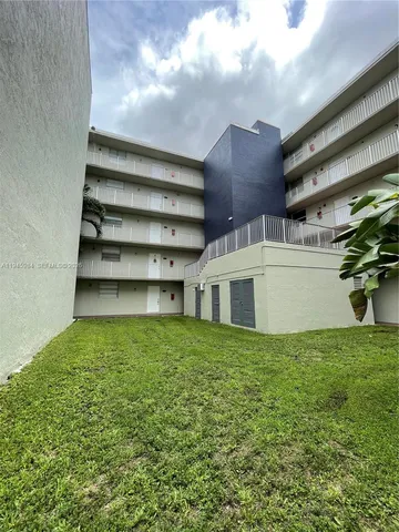 a view of a house with a yard and a large tree
