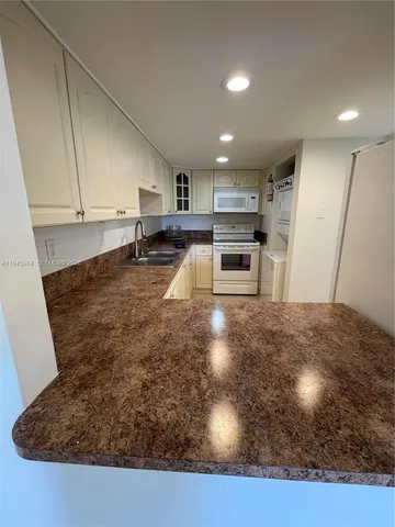 a kitchen with kitchen island a sink a stove and refrigerator