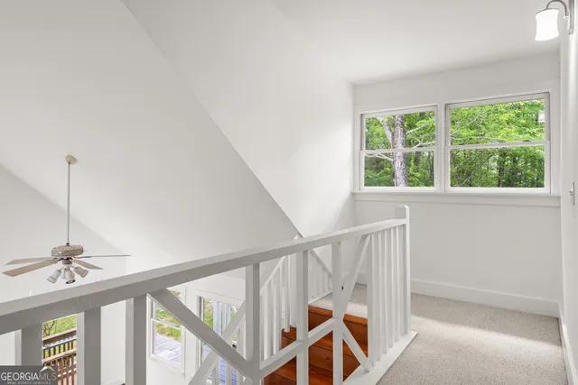 an empty room with windows and chandelier fan