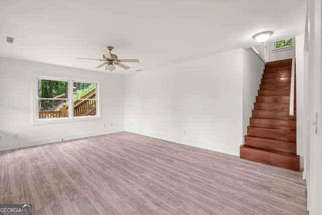 a view of an empty room with a window and wooden floor