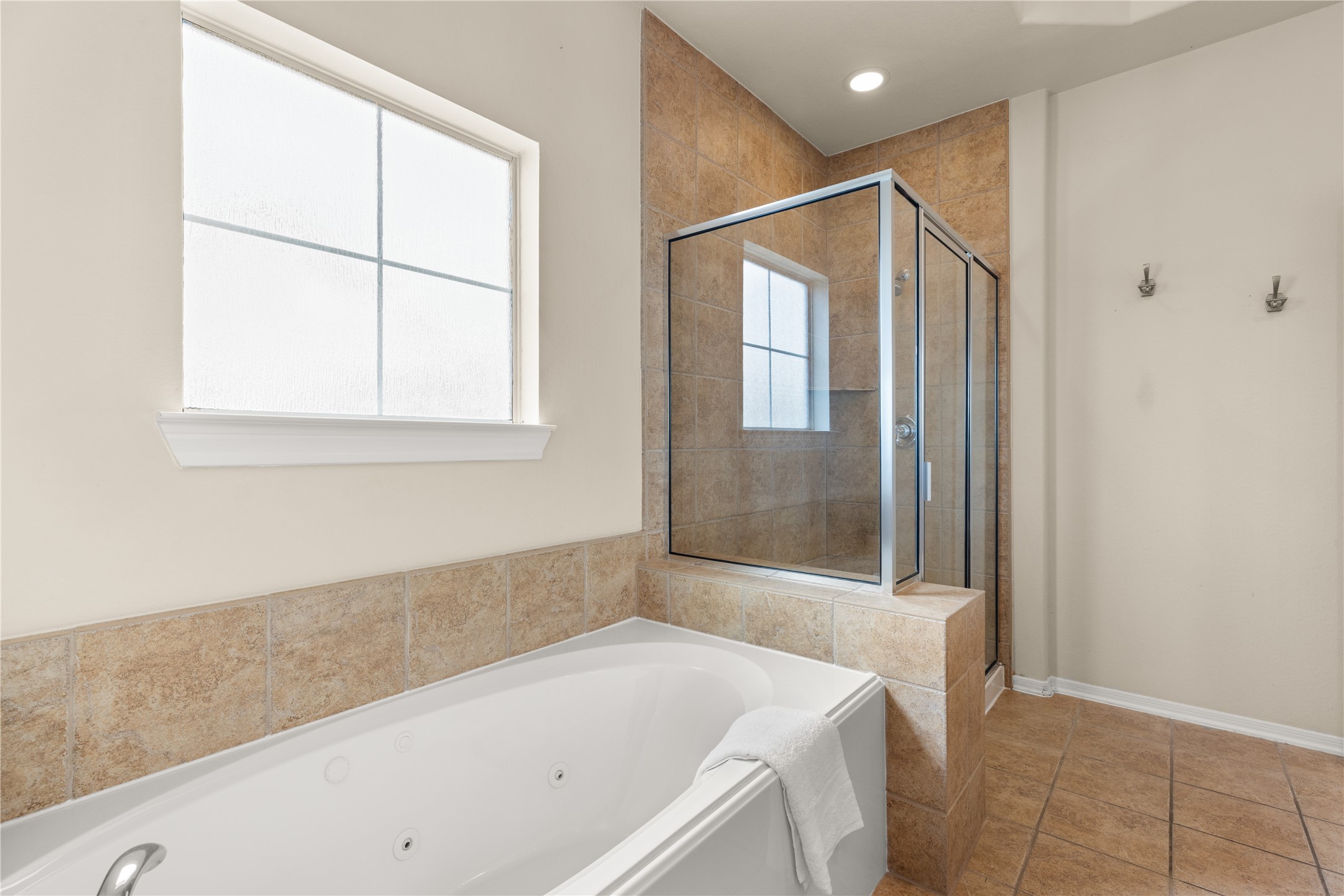 3334 Clearview Villa Way Houston, TX 77025 - Photo 20 of 35 This bathroom features a sleek, modern design with a spacious glass-enclosed shower and a relaxing bathtub. The neutral tile and large frosted window provide a bright and inviting atmosphere.