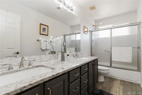 a bathroom with a granite countertop sink a toilet and a large mirror