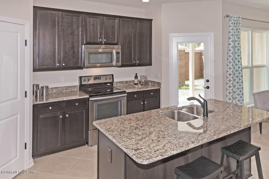 1708 Sanctuary Way Fleming Island, FL 32003 - Photo 11 of 21 a kitchen with kitchen island granite countertop a wooden cabinets and a stove