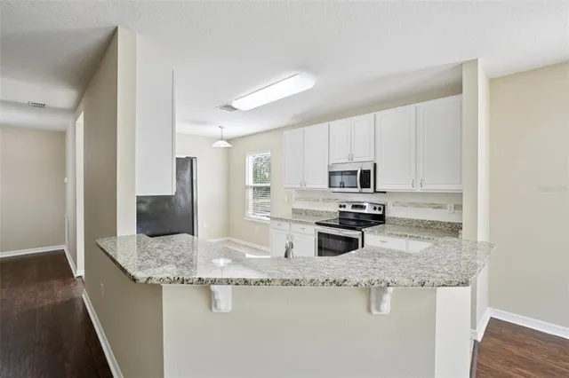 a kitchen with granite countertop kitchen island a sink appliances and cabinets