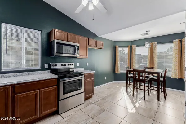 a kitchen with stainless steel appliances granite countertop a stove top oven a sink a dining table and chairs