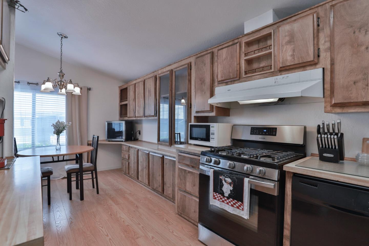 11662 North Ham Lane, Unit 62 Lodi, CA 95242 - Photo 11 of 25 a kitchen with stainless steel appliances granite countertop a stove top oven a sink a dining table and chairs with wooden floor