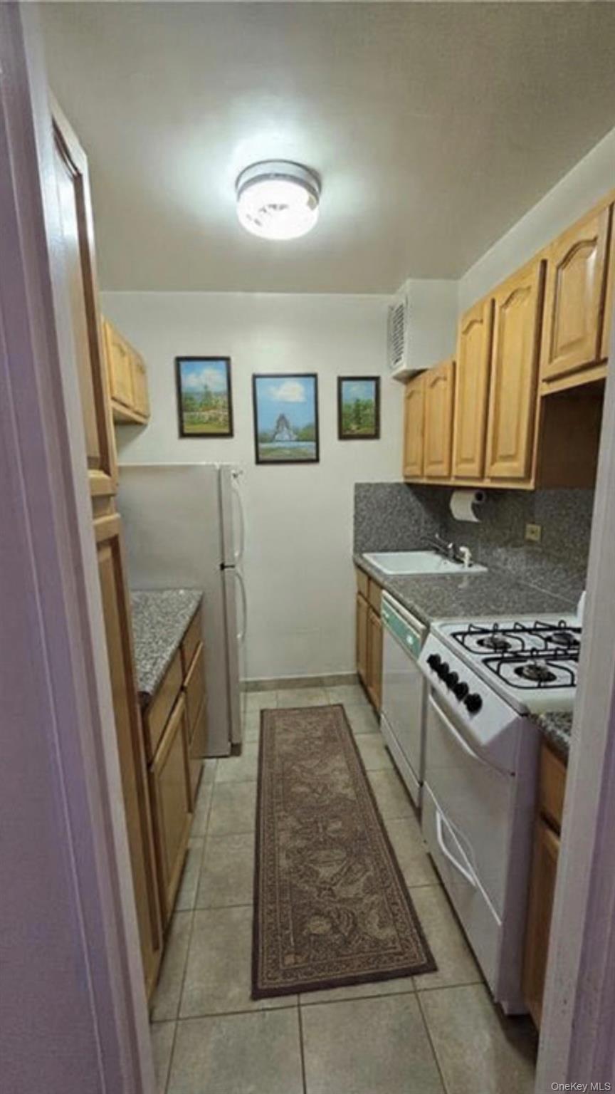 142-05 Roosevelt Avenue, Unit 602 Queens, NY 11354 - Photo 3 of 6 a kitchen with granite countertop a refrigerator and a stove