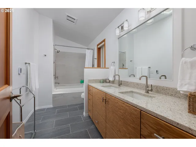 a bathroom with a sink double vanity granite tub shower and a mirror