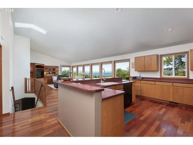 a kitchen with a kitchen island wooden floors and a view of living room