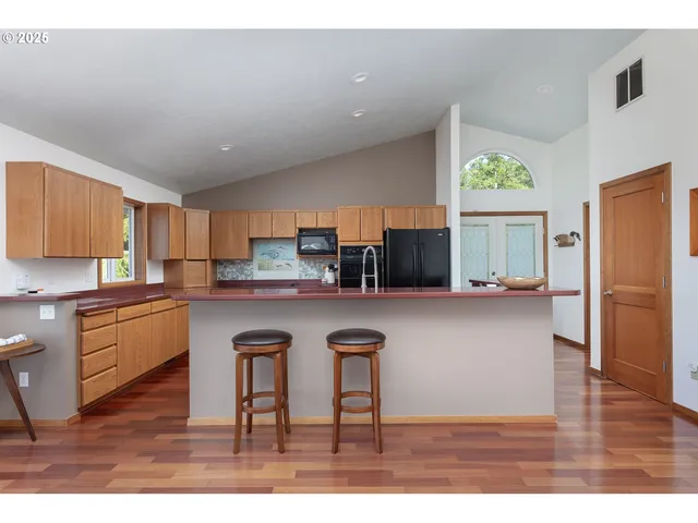 a kitchen with stainless steel appliances granite countertop a refrigerator a sink dishwasher a stove and white countertops with wooden floor