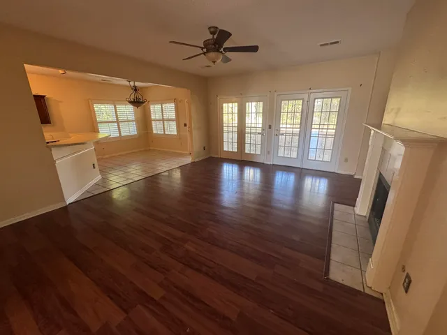 a view of empty room with wooden floor and fan