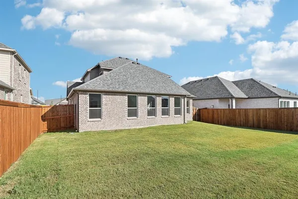 a view of an house with backyard area and wooden fence