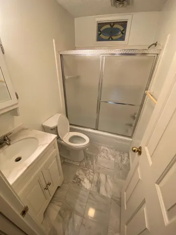 a bathroom with a granite countertop sink toilet and shower