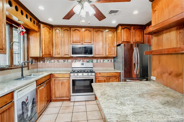 a kitchen with stainless steel appliances granite countertop a refrigerator a sink dishwasher a stove and oven with wooden cabinets