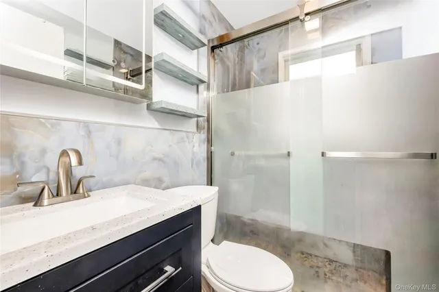 a bathroom with a granite countertop sink a toilet a shower and a mirror