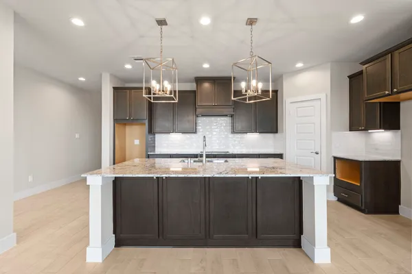 a kitchen with kitchen island granite countertop a sink and refrigerator