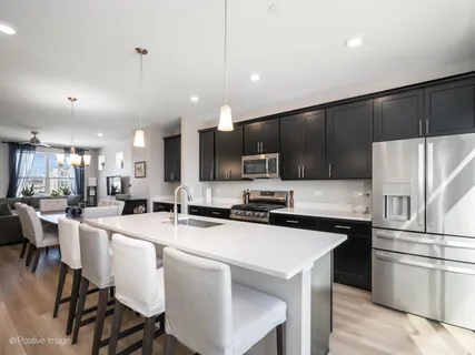a kitchen with a sink a stove a refrigerator and chairs