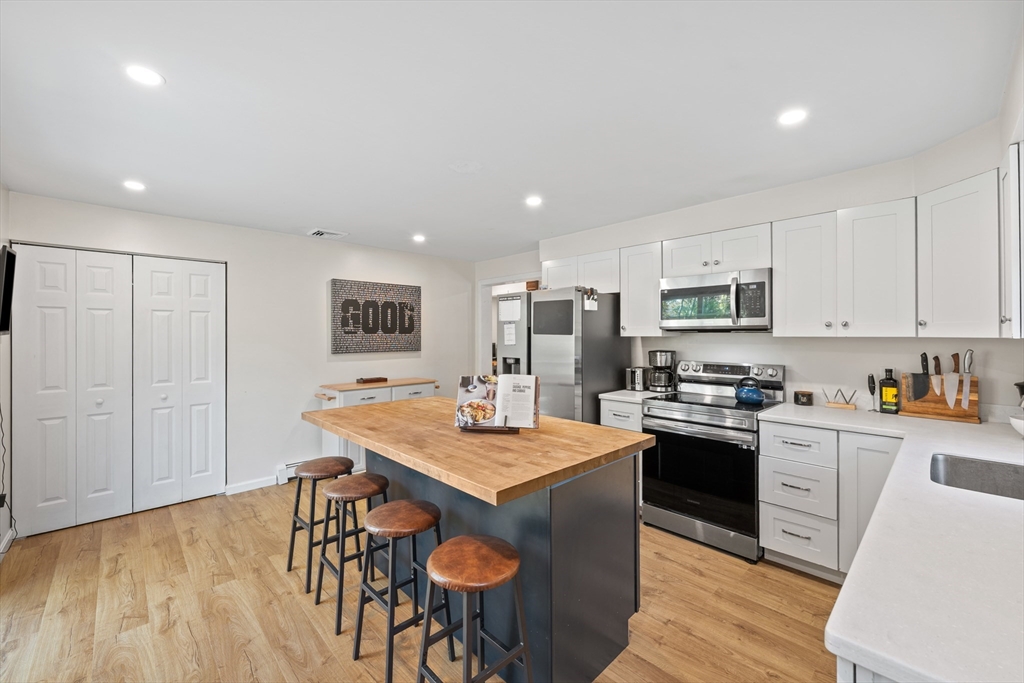 89 River Road Sturbridge, MA 01566 - Photo 4 of 31 a kitchen with stainless steel appliances granite countertop a stove top oven a refrigerator a sink and a dining table with wooden floor