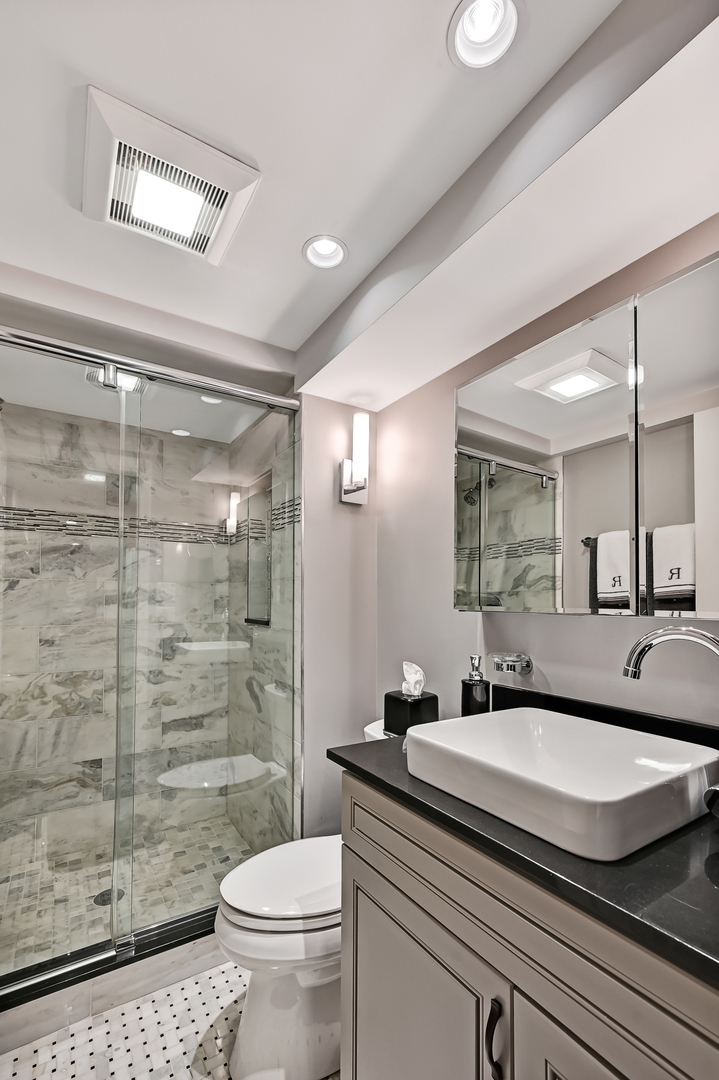 2 Hampton Court Burr Ridge, IL 60527 - Photo 33 of 38 a bathroom with a granite countertop sink a toilet a mirror and shower