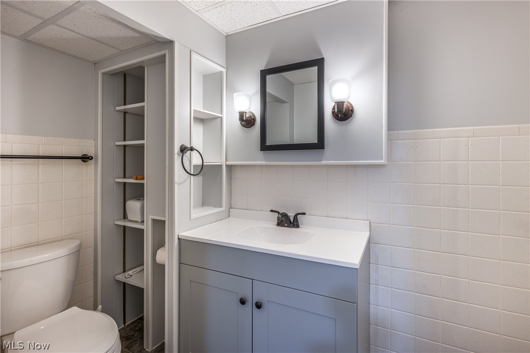 29220 Ridge Road Wickliffe, OH 44092 - Photo 27 of 34 Bathroom with a paneled ceiling, tile walls, toilet, and vanity