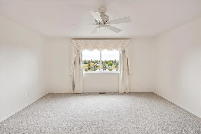 an empty room with a window and a ceiling fan