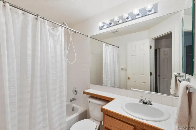a bathroom with a granite countertop sink mirror vanity and toilet