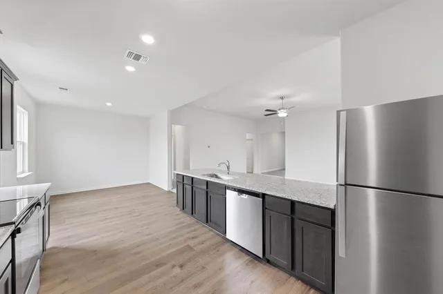 a kitchen with stainless steel appliances granite countertop a refrigerator a sink and a stove top oven