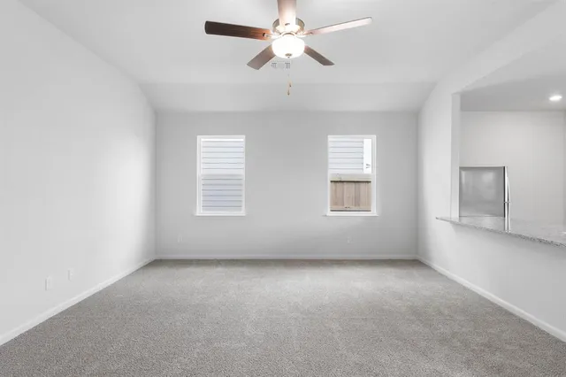 an empty room with chandelier fan and windows