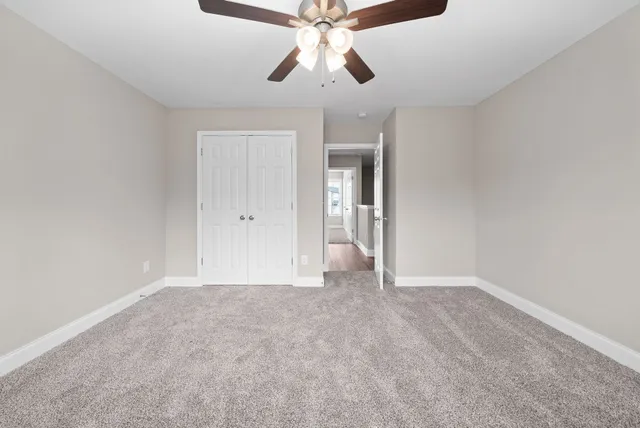 a view of an empty room and chandelier fan