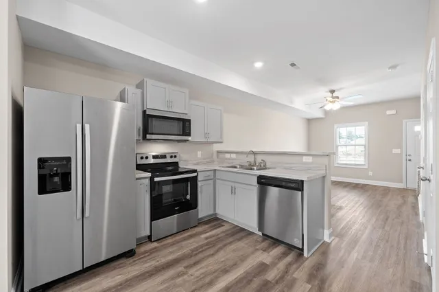 a kitchen with stainless steel appliances granite countertop a stove top oven a refrigerator and a sink