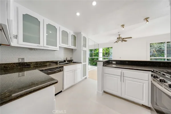 a kitchen with granite countertop white cabinets and stainless steel appliances