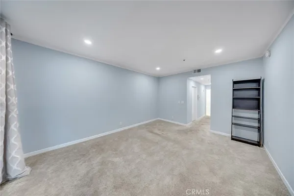 a view of walk in closet with clothes and lots of frames on wall