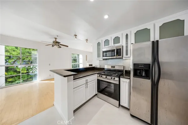a kitchen with stainless steel appliances granite countertop a stove a refrigerator and a microwave