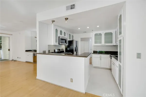 a kitchen with stainless steel appliances granite countertop a refrigerator sink and white cabinets