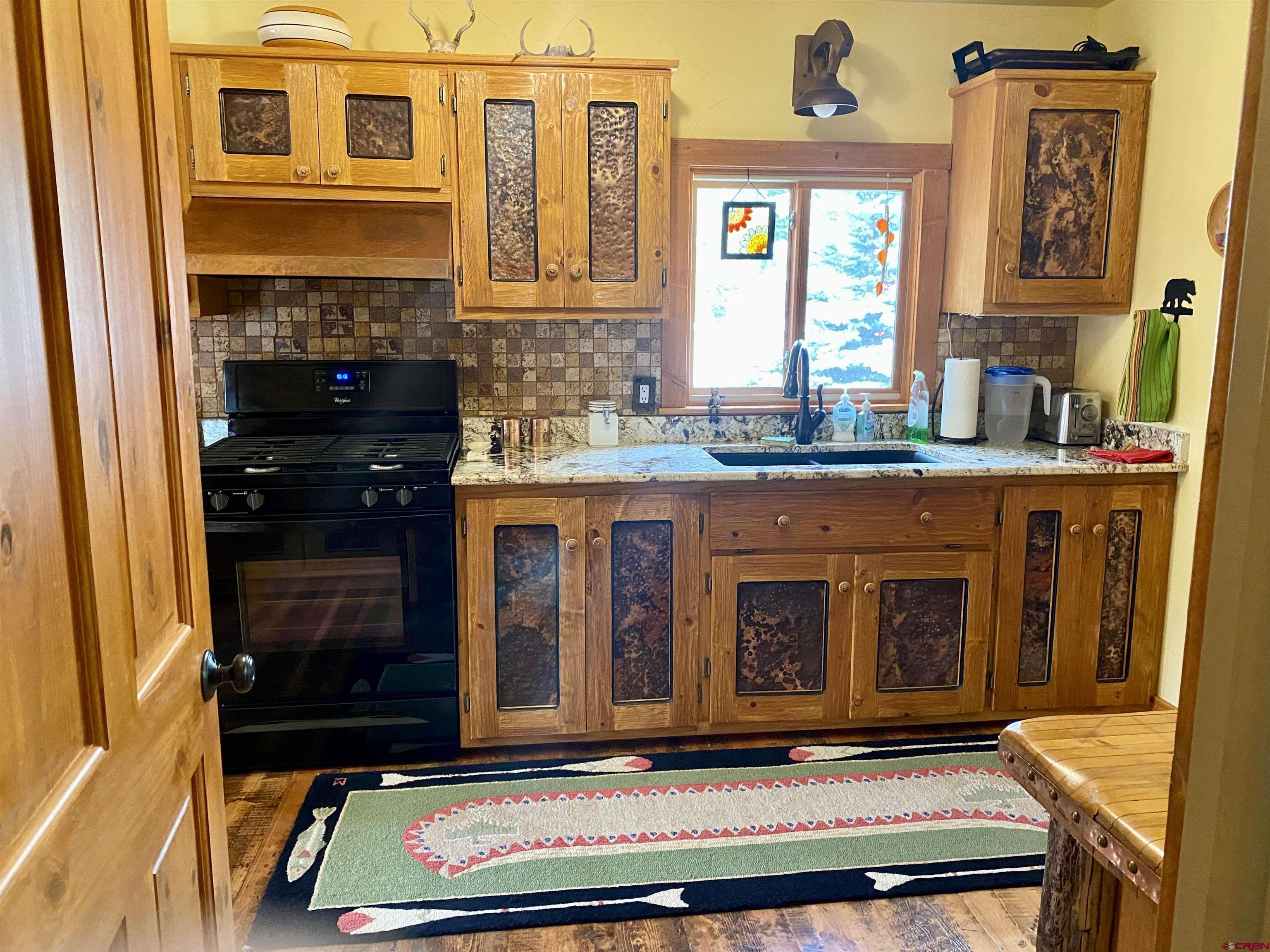 480 Bear Trail Montrose, CO 81403 - Photo 8 of 35 a living room with kitchen island granite countertop furniture and a fireplace