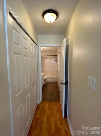 a view of a hallway with wooden floor and closet
