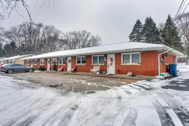 a view of a white house with large windows next to a road