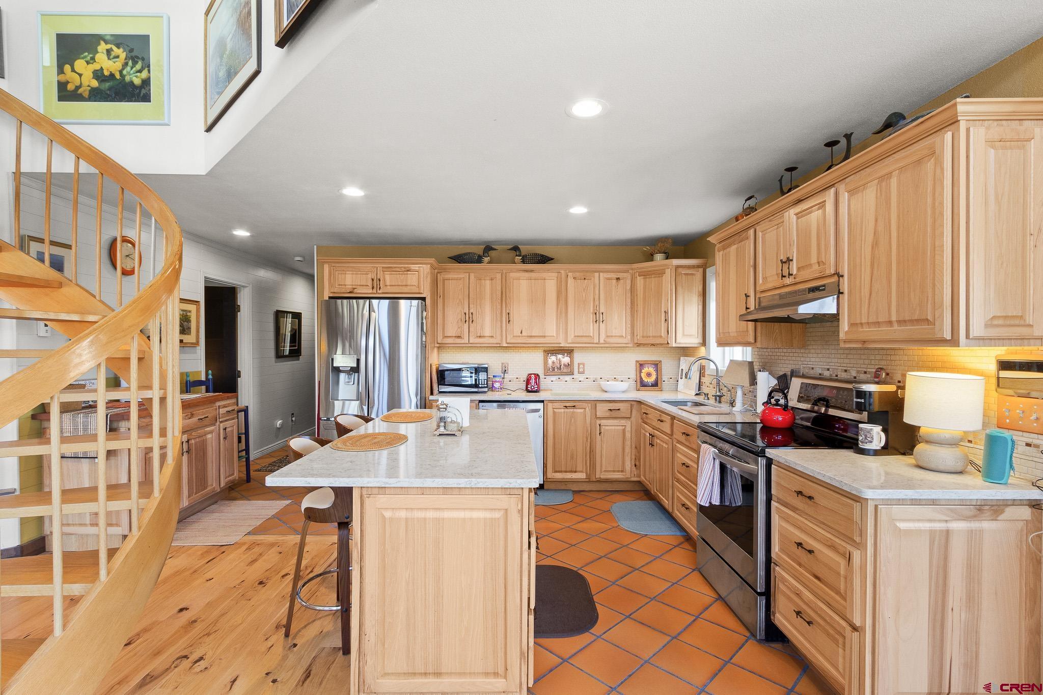 13720 6000th Road Montrose, CO 81403 - Photo 12 of 36 a kitchen with stainless steel appliances kitchen island granite countertop a refrigerator a sink dishwasher and white cabinets with wooden floor