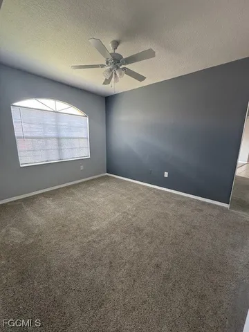 en empty room with windows and chandelier fan